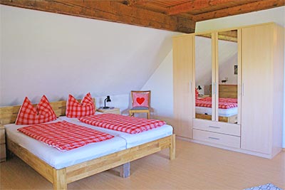 Schlafzimmer mit Doppelbett und zwei Einzelbetten
